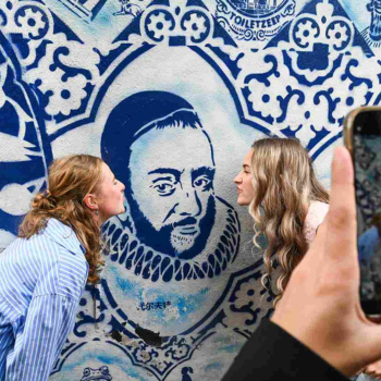 Twee meiden poseren voor een Delfts Blauwe muur