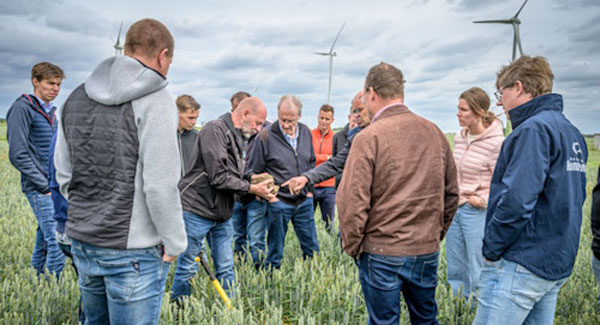 Boeren inspecteren een klomp klei op de proefakker