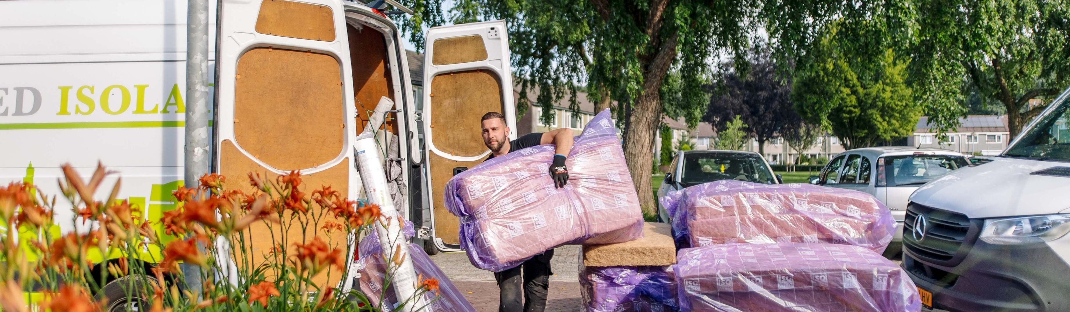 Medewerker isolatiebedrijf tilt isolatiemateriaal vanuit de bus naar het huis