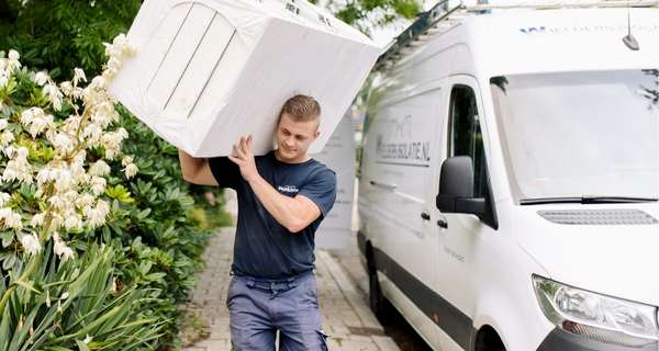 Medewerker isolatiebedrijf tilt isolatiemateriaal vanuit de bus naar de woning