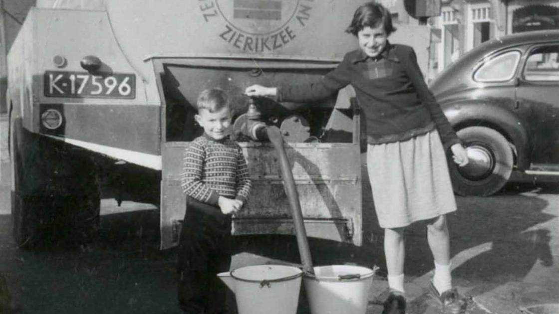 Twee jonge kinderen bij auto met watertank