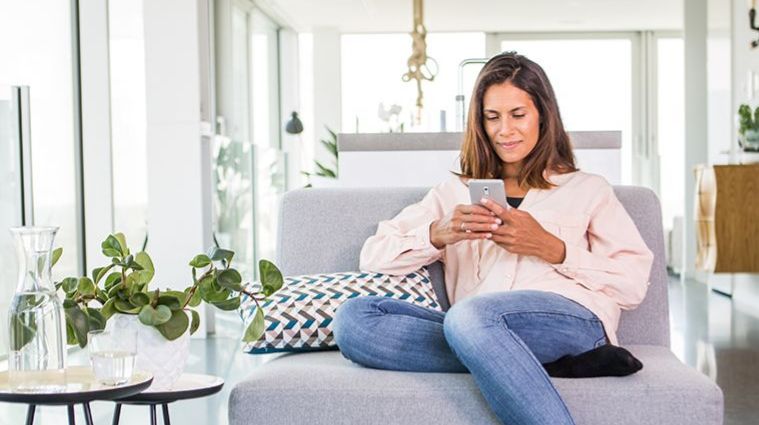 Vrouw met mobiele telefoon op bank