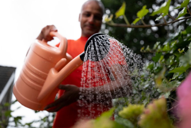 Man met gieter in tuin