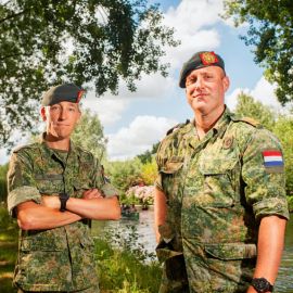 Twee veteranen in veteranentenue poseren op een steiger bij het water.