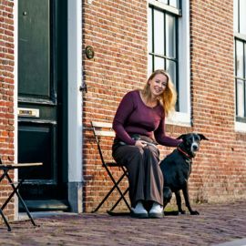 Dame met haar hond voor haar huis.