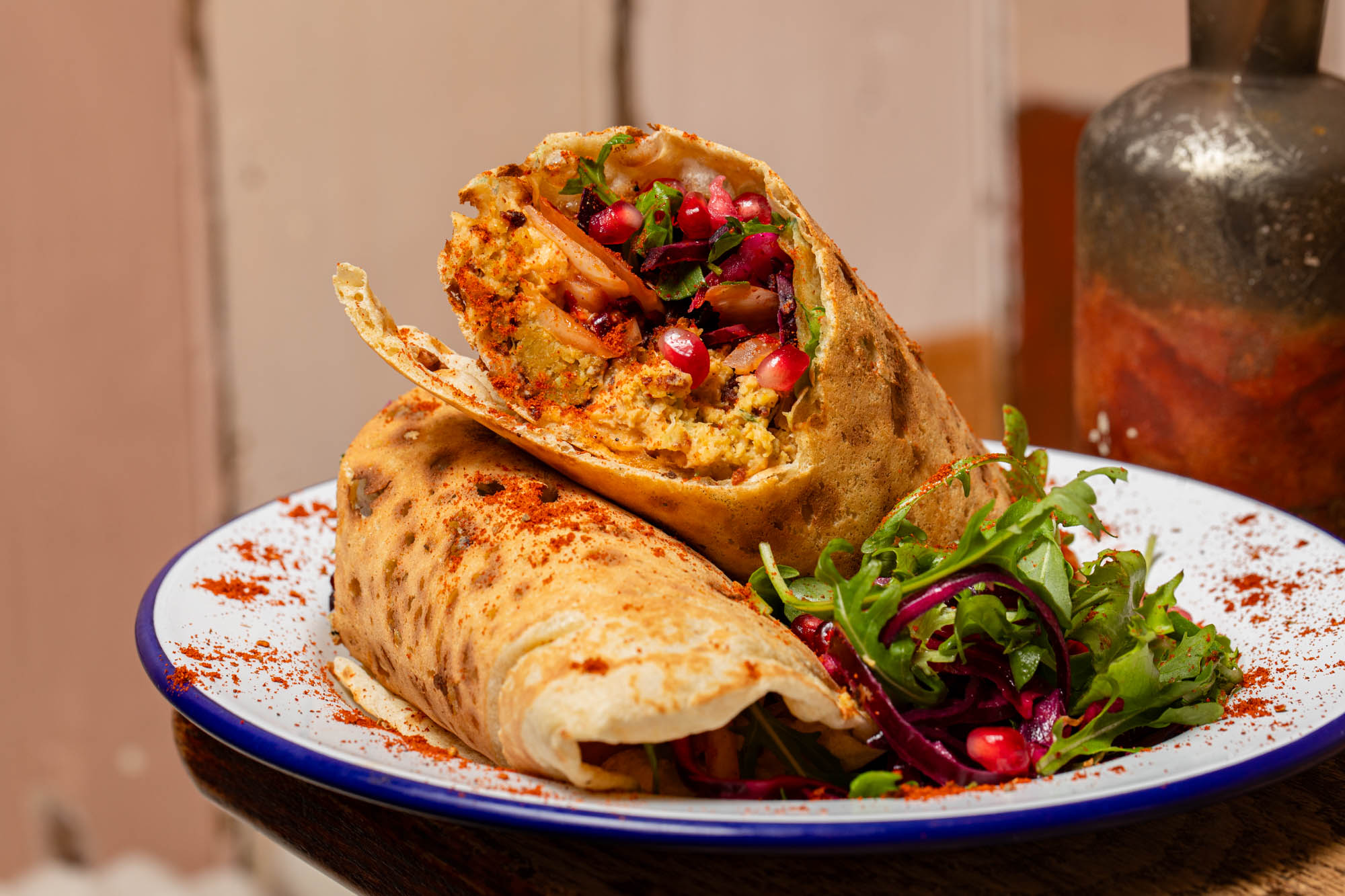 delicious looking flatbread wraps with pomegranate seeds on a white plate with a blue rim