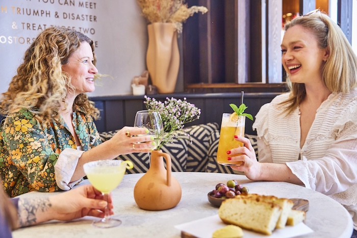 two ladies having small bites and cocktails